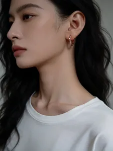 Detailaufnahme minimalistischer quadratischer Creolen in Rosegold am Ohr getragen.