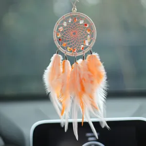 Close-up of orange and white feather dreamcatcher car ornament with natural stones