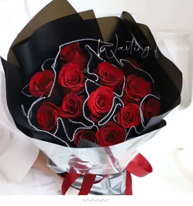Detailed view of stunning red rose bouquet wrapped in elegant black paper and pearl mesh.