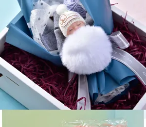 Decorative shredded paper and cute sleeping baby doll gift box set for festive packaging.