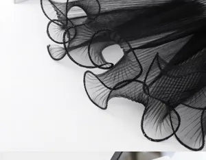 Close-up detail of black pleated ruffled mesh tulle, elegant wavy edge for floral wrap.