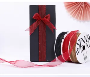 Close up detail view of wavy edge organza ribbon with spool and gift box bow decoration.