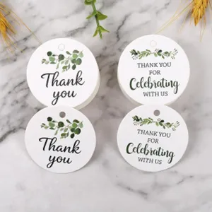 Detailed close-up of round paper gift hang tags featuring botanical eucalyptus leaf patterns.