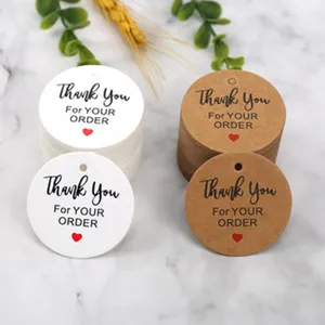 Round kraft paper and white gift tags close up showing thank you print and heart.