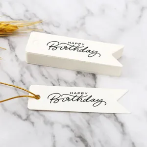 Detail view of white swallowtail birthday gift paper tags with elegant black typography.