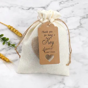 Detail view of white burlap gift bag with craft paper tag, heart cutout, and rustic rope string.