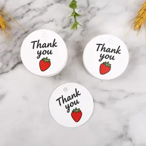 Detailed close-up of round paper gift tags featuring sweet strawberry print and thank you text.