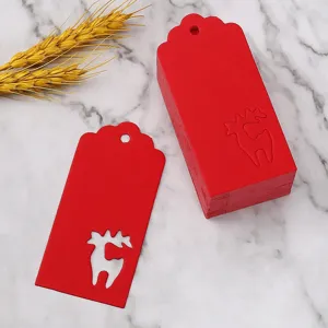 Close-up detail of red Christmas paper tags with deer cutout design on marble surface.