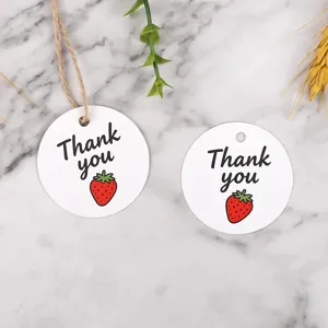 Detail shot of round paper gift hang tags with strawberry print and thank you text.