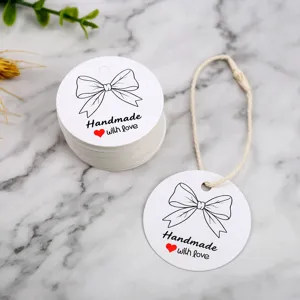 Round white handmade paper gift tags with cute bow illustration and string for packaging decor.