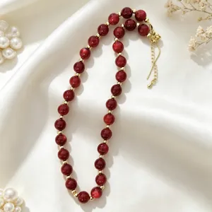 Detailed view of a chic red acrylic bead necklace with gold spacers on white silk.