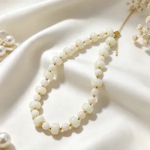 Elegante Acryl-Perlenkette Detailaufnahme mit goldenen Akzenten auf weißem Seidenhintergrund.