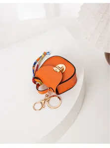 Mini llavero bolso de silla naranja con herrajes dorados y pañuelo de seda, accesorio moderno.