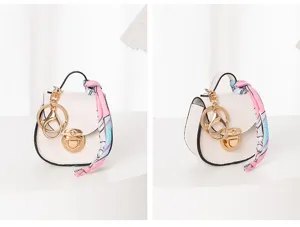 Mini bolso de silla de montar blanco llavero de cuero con herrajes dorados y cinta rosa.