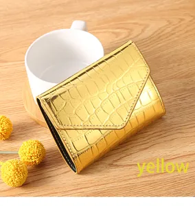 Detail view of a shiny gold crocodile pattern women wallet on wooden table with cup.