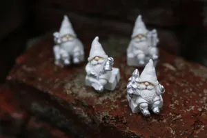 Gros plan de quatre figurines de père noël en résine blanche assises sur des blocs de déco de noël.
