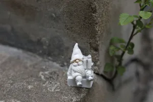Figurine de pere Noel en resine blanche avec cadeau pour decoration de fete de Noel.