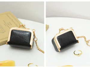Close-up detail view of mini black PU leather kiss-lock coin purse with gold chain.