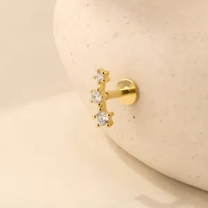 Dettaglio di piercing orecchio dorato con tre zirconi