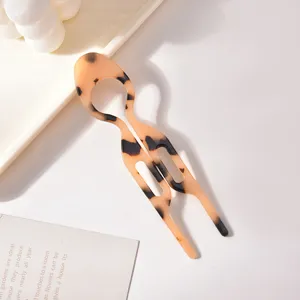 Dettaglio di elegante forcina per capelli tartarugata con design simmetrico a forma di U