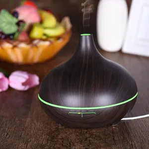 Dark wood grain essential oil diffuser with green LED light on wooden table
