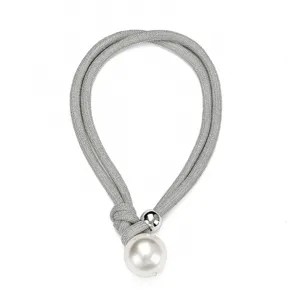Macro detail of a silver mesh choker necklace featuring a large faux pearl and metal bead