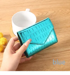 Close-up detail of the glossy metallic blue crocodile pattern women wallet on wooden desk.