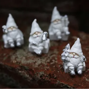 Ensemble de 4 figurines de gnomes de Noël en résine blanche avec détails argentés.