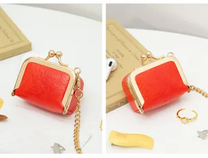 Close-up detail of a red PU leather mini kiss-lock coin purse with gold chain and metal frame.