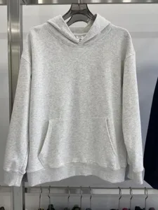 Detalle de la sudadera con capucha gris de felpa pesada, colgada con textura y bolsillo.