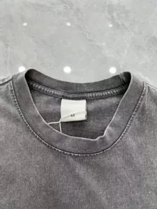 Close-up detail of vintage washed charcoal grey t-shirt collar neckline with size M tag.