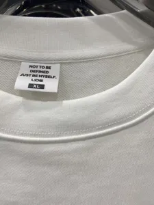 Close-up detail shot of white hoodie collar with brand neck label and XL size tag.
