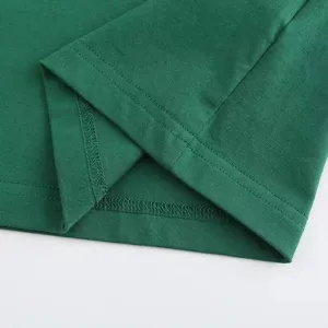 Close-up detail of the green t-shirt hem showcasing fine double-needle stitching quality.