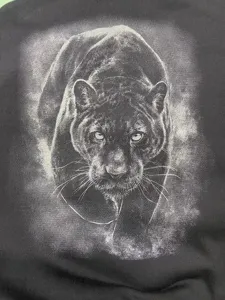 Detalle de sudadera con capucha negra pesada con estampado gráfico detallado de pantera salvaje.