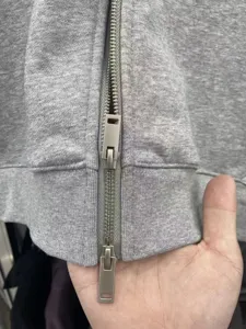 Close-up detail view of the metal double zipper and heavy grey fleece hoodie fabric.