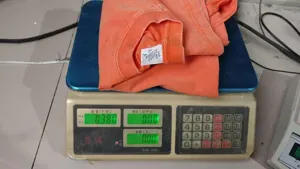 Detail view of the orange heavy weight vintage washed cotton t-shirt on digital scale display.