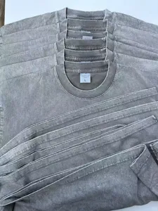 Close-up detail of heavy vintage acid-washed grey short sleeve t-shirt fabric texture and collar tag.