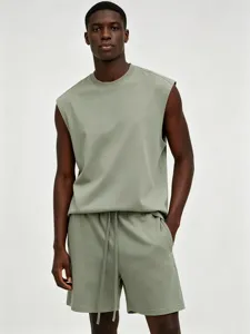 Close-up detail of the men's sleeveless tank top and drawstring shorts set in solid light green.
