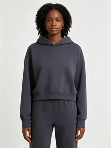 Gros plan détaillé du sweat à capuche court en bouclette gris foncé porté par le mannequin.