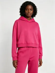 Détail de sweat à capuche rose court, présentant une belle matière molletonnée et tendance.