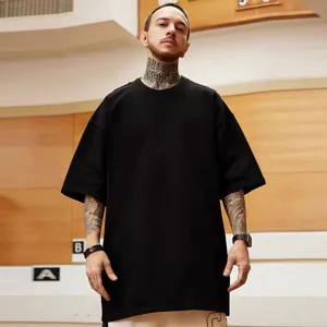 Vista detallada de la camiseta negra lisa oversize con hombros caídos usada por un modelo masculino.