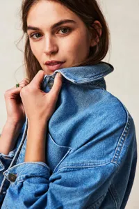 Women's casual blue denim jacket with lapel collar and metal button front detailing.