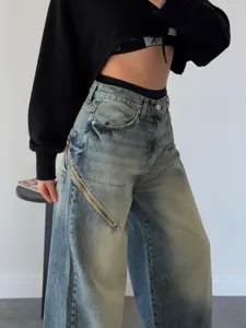 Jean femme délavé vintage à jambes larges avec détail de fermeture éclair diagonale stylée.