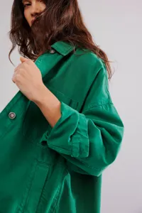 Detailed view of women green denim jacket with chest pockets and metal buttons close up