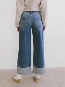 Details of women's casual wide leg washed blue denim jeans with big cuffs and knit sweater.