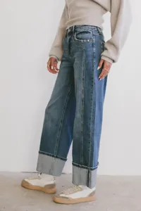 Close-up detail shot of wide-leg washed denim jeans featuring cuffed hems and two-tone panel.