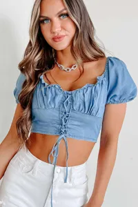 Close-up detail of a blue denim crop top featuring puff sleeves and a chic lace-up front design.