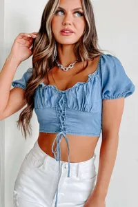 Close-up detail of women blue denim crop top with puff sleeves and lace-up front design.
