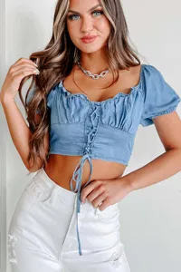 Closeup of a stylish blue denim crop top featuring puff sleeves and lace-up front detail.