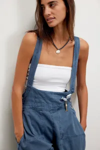 Vue détaillée du pantalon en denim sans manches, coupe décontractée et boutons métalliques.